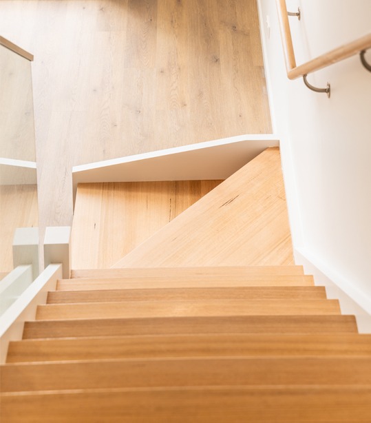 Top view of modern timber staircase with angled landing and glass balustrade