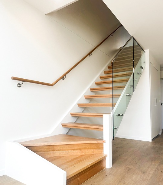 Timber staircase with glass balustrade and minimalist handrail in modern home interior